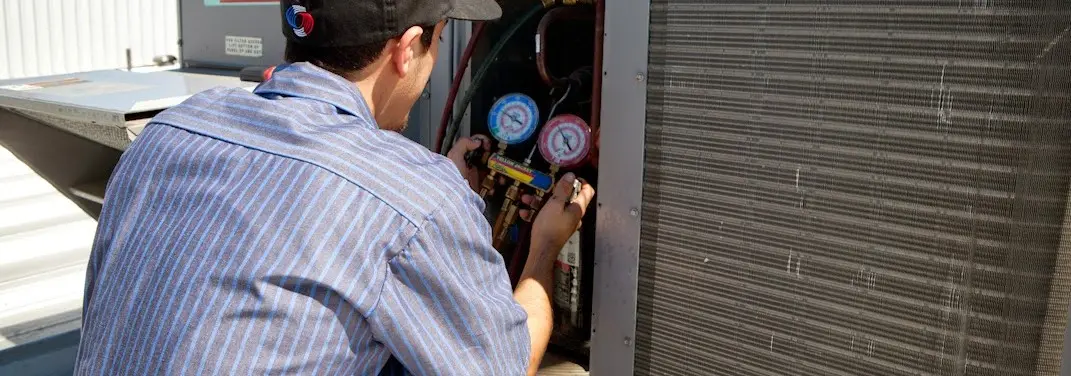 HVAC technician servicing a condenser unit in Marina